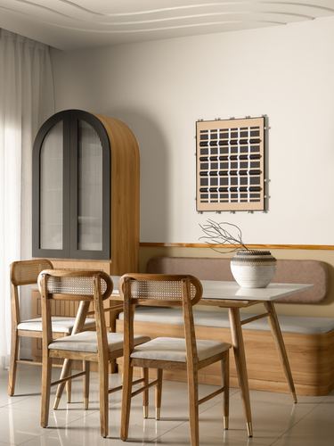 Dining nook with cane chairs, arched wooden cabinet, and banquette seating against warm neutral walls