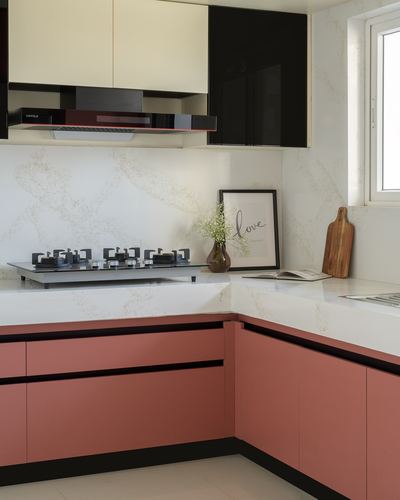 L-shaped kitchen counter with terracotta cabinets, white veined countertop, black chimney hood and styled decor