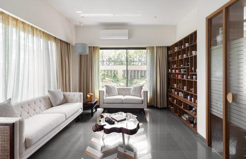 Living room with cream sofas, live-edge wood coffee table, and wooden display shelving of mugs.