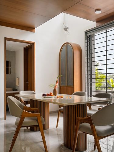 Dining room with fluted wood-based marble table, arched cabinet, and slatted window in Ahmedabad home