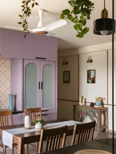 Dining room with mauve arched wardrobe, wooden table, and warm-toned hallway beyond