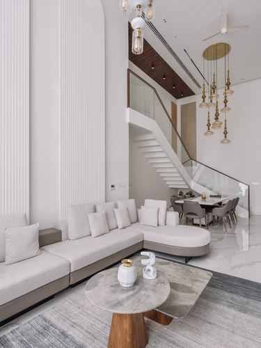 Double-height living room with beige sectional, floating staircase and hanging glass pendant cluster