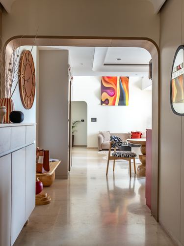 Foyer with wooden arch and round clock opening into a living room with abstract art