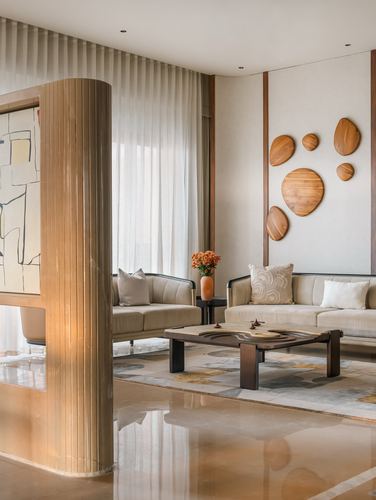 Living room with fluted wood column, beige sofas, and organic wood discs on wall