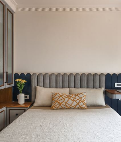 Bedroom with scalloped navy headboard, striped upholstery, and wooden bedside cabinet with flowers