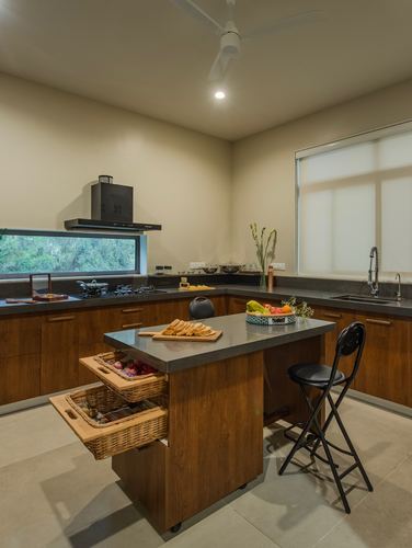 Wood-toned kitchen with island holding cane baskets, stone counters, and a window overlooking greenery