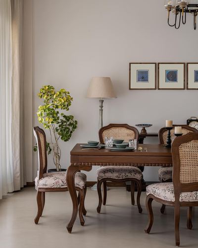 Victorian-style dining room with carved wood table, cane chairs, and framed art