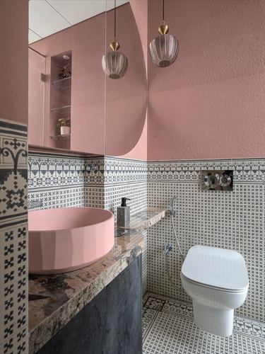 Pink powder room with patterned tiles, round pink sink, and two pendant lights