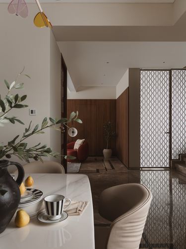 Marble dining table foreground with view through jali screen door to wood-paneled lounge beyond