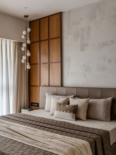 Bedroom with wood-paneled wardrobe, textured plaster wall, upholstered headboard, and globe pendant chandelier