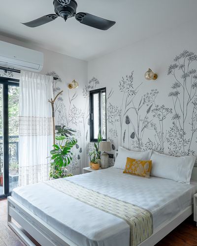 White bedroom with botanical line-art wallpaper, brass sconces, and balcony with sheer curtains