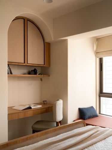 Arched wardrobe above a wooden study desk beside a window seat with terracotta cushion