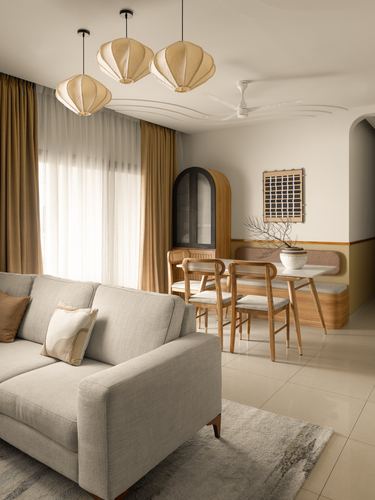 Living and dining area with lantern pendants, cane chairs, arched cabinet, and beige sofa
