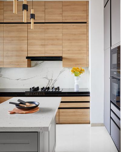 Modern kitchen with wood cabinetry, marble-look backsplash, black countertop cooktop and island