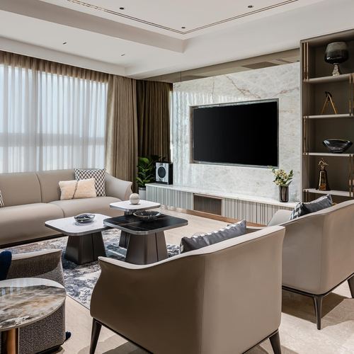 Beige living room with marble TV wall, layered coffee tables and taupe armchairs