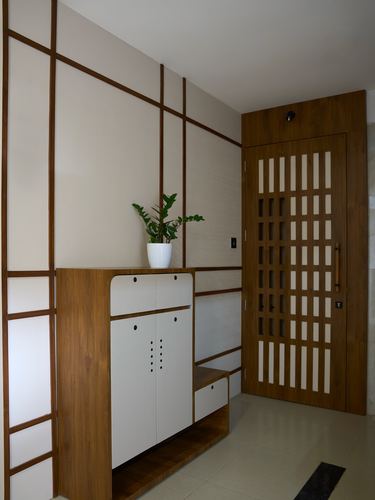 Entryway with wood-grid wall paneling, white cabinet, plant, and slatted wooden door