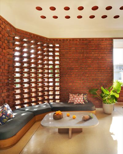 Corner seating nook with brick jali screen, terracotta ceiling dots, and stone coffee table
