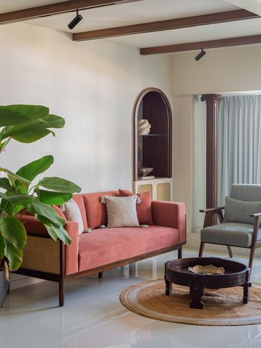 Living room with pink velvet sofa, arched wooden niche, and round jute rug