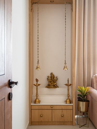 Wooden pooja unit with brass Ganesha idol, hanging bells, and diyas beside a curtained window