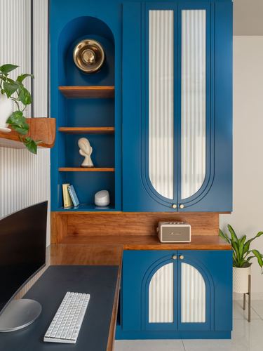 Teal cabinetry with arched glass doors and wood shelving niche above a study desk