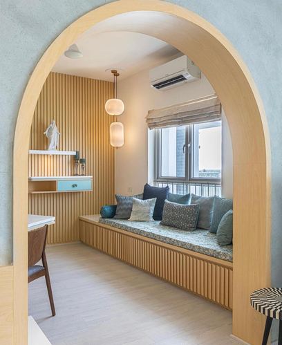 Arched wooden doorway framing a fluted-panel window seat with blue cushions and pendant lights
