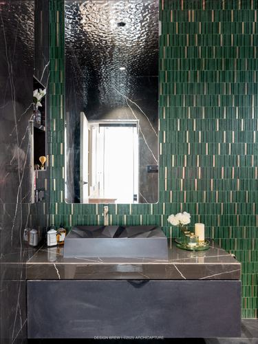Bathroom vanity with green ribbed tile wall, marble mirror surround, and faceted dark sink