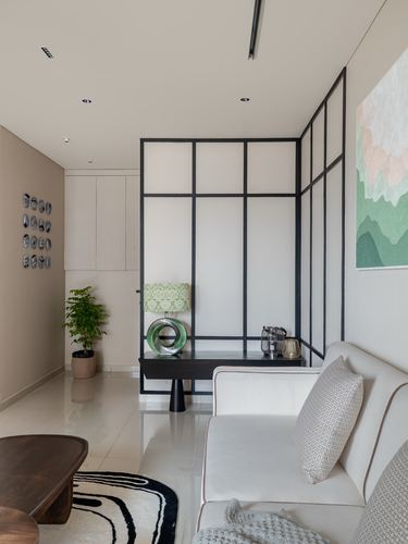 Living room with black-framed glass partition, cream sofa, and dark console table