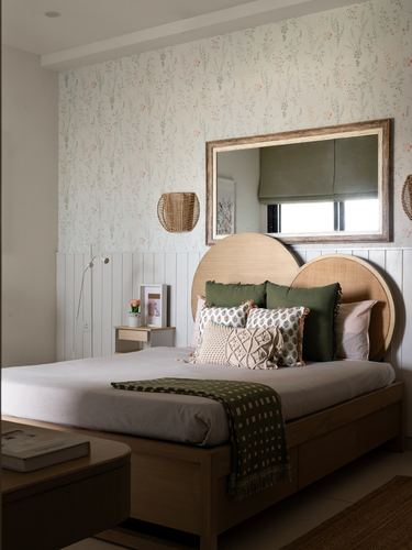 Bedroom with floral wallpaper, wainscoting, and a bed with round cane headboards and green cushions