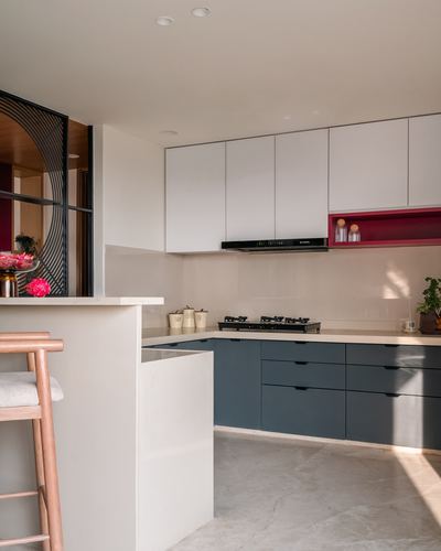 Modern white and blue kitchen with island counter, gas hob and round decorative mirror
