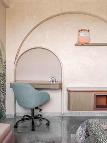 Arched study nook with sage chair, wooden desk, and plush toy on shelf