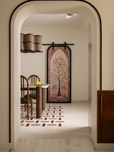 Arched doorway framing a dining nook with a painted sliding panel and woven pendant light