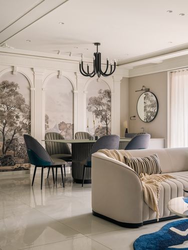 Living-dining space with arched mural panels, black chandelier, and beige channel-tufted sofa