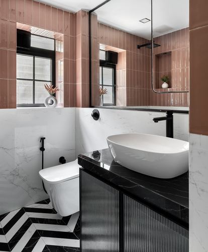 Pink-tiled bathroom with black marble vanity, oval basin, and chevron floor tiles