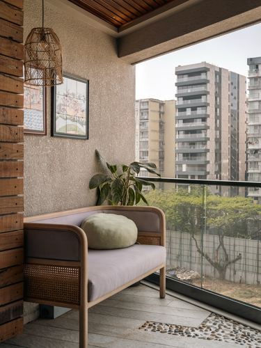 Cane bench with lavender cushions on a textured balcony overlooking Mumbai high-rises