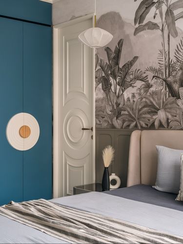 Bedroom corner with teal wardrobe, circular wall decor, white paneled door, and jungle mural behind upholstered bed