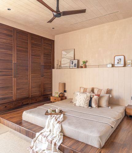 Japandi bedroom with walnut wardrobe wall and raised platform bed on wooden plinth