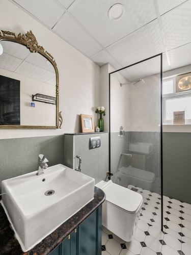 Bathroom with ornate gold mirror over marble-top vanity, glass shower, patterned tile floor