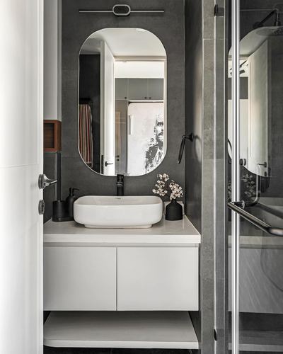 Bathroom with dark stone wall, white floating vanity, oval mirror, and black fixtures