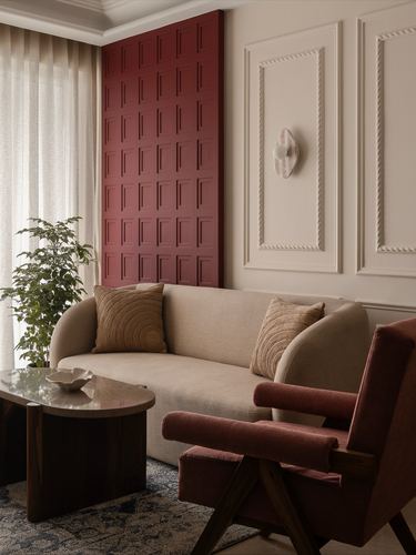 Living room corner with cream sofa, burgundy armchair, and panelled burgundy accent wall