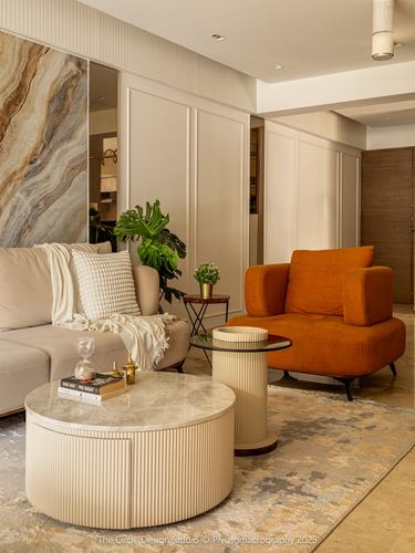 Living room with beige sofa, orange armchair, fluted coffee table, marble panel wall