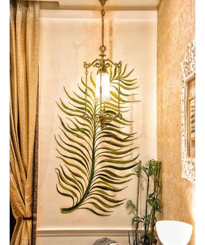 Brass lantern pendant hangs in front of a large painted palm leaf mural in a warm-toned foyer