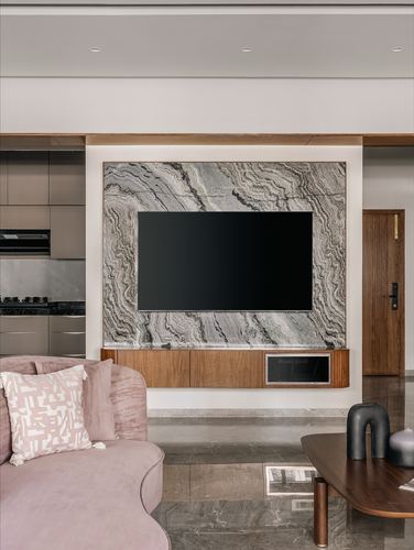 Living room with veined stone TV wall, wooden console, and pink velvet sofa
