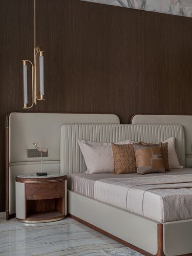 Bedroom corner with channel-tufted headboard, round wood nightstand, and brass pendant light