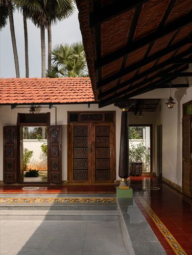 Carved wooden doors and sloped tile roof at entrance of a Chettinad-style courtyard home