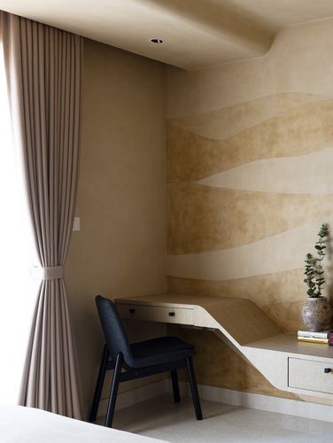 Corner study nook with wave-patterned limewash wall, floating wood desk, and black chair