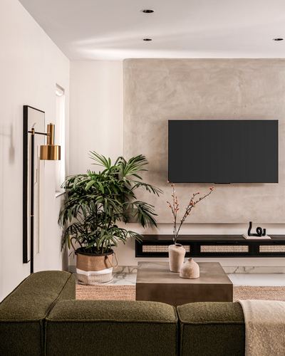 Living room with olive boucle sofa, plaster wall, wall-mounted tv and cane console