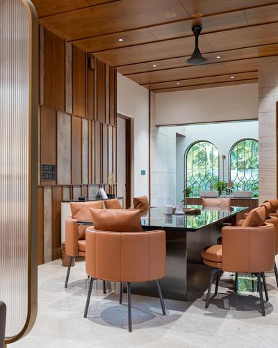 Dining area with tan leather chairs around a dark stone table beneath a wood-slat ceiling