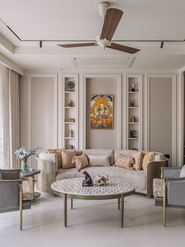 Symmetrical beige living room with curved sofa, wall niches and a round mosaic coffee table