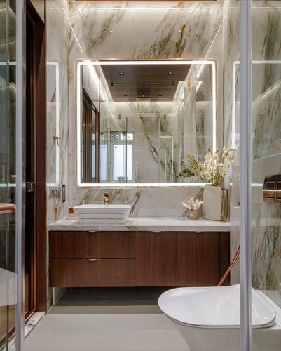 Marble bathroom with backlit mirror, wood vanity, vessel sink and wall-hung toilet in Mumbai apartment