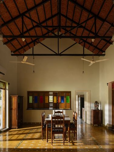 Traditional dining hall with exposed truss roof, patterned tile floor, and stained-glass window